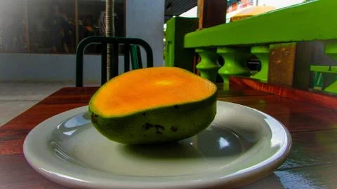 Mango Fruit on a plate cut in half sitting in the open street. Stock Photos
