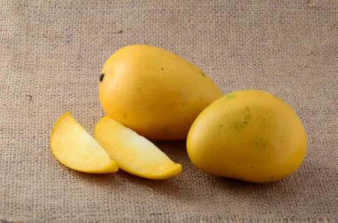 Mango fruit with slice on sack cloth background Stock Photos