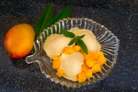 Mango ice cream with fresh mango slices with leaves mint on a glass plate. Stock Photos