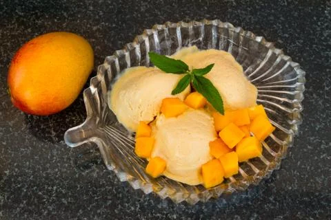 Mango ice cream with fresh mango slices with leaves mint on a glass plate. Stock Photos