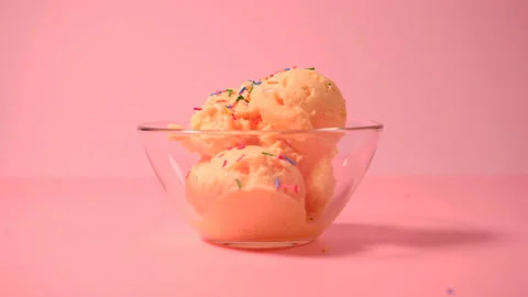 Mango ice cream in a glass bowl. Scoop of mango ice cream sprinkled with colored Stock Footage 165997953