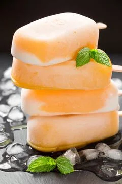 Mango ice cream popsicles stacked on a bed of ice with fresh mint leaves adding Stock Photos