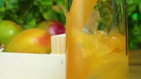 Mango Juice Poured Into Glass Next to Mango in Wooden Crate Stock Footage 334337601