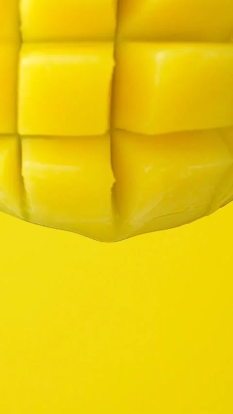 Mango juice slowly dripping from fresh fruit, yellow background, vertical macro Stock Footage 328849202