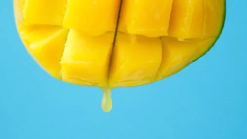 Mango juice slowly dripping from fresh fruit, blue background. Stock Footage 329885063