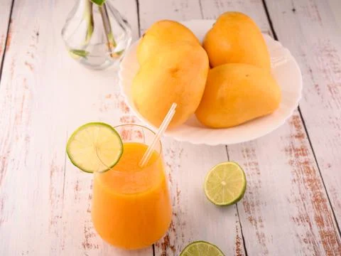 Mango mocktail with lime slice and plate of mango and lime Stock Photos
