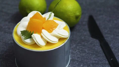 Mango mousse cake Tin Can garnished with cream rosettes, peach wedges, mint Stock Footage 313293884