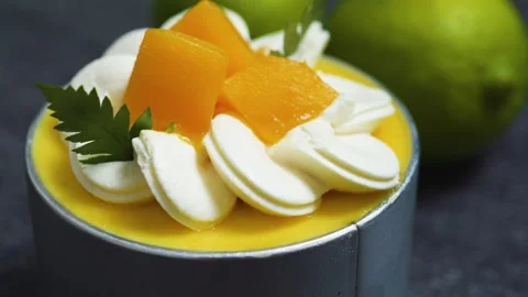 Mango mousse cake Tin Can garnished with whipped cream, fresh mango slices, Stock Footage 313293898