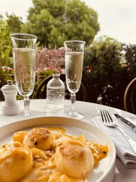 Mango mousse with sliced ripe mango on the side, two glasses of champagne on the 库存照片