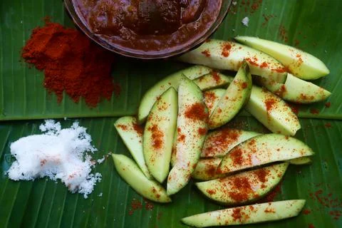 Mango pickle raw mango sliced with chilly salt and placed on banana leaves Stock Photos