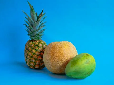 Mango, pineapple and melon on a blue background Stock Photos