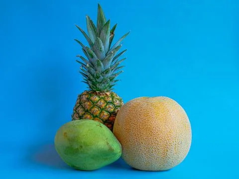 Mango, pineapple and melon on a blue background Stock Photos