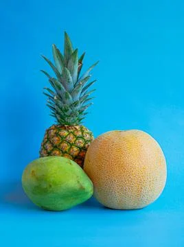 Mango, pineapple and melon on a blue background Stock Photos