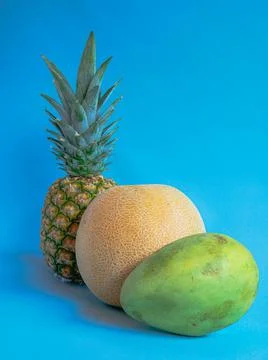 Mango, pineapple and melon on a blue background Stock Photos