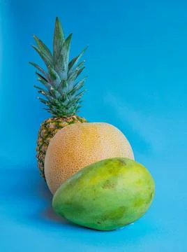 Mango, pineapple and melon on a blue background Stock Photos