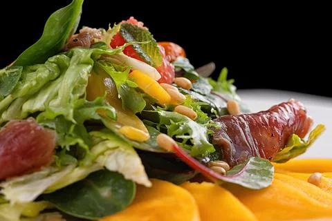 Mango salad, with jerky, grapefruit, pine nuts and mint, on a white plate, .. Stock Photos