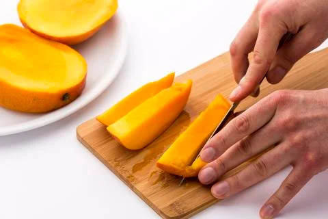 Mango slice being cut into four fruit chips Stock Photos