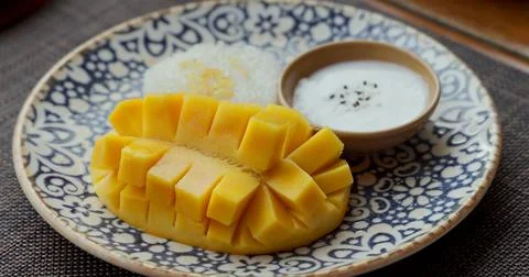Mango sticky rice dessert on patterned plate, traditional Thai cuisine Stock Photos