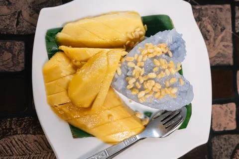 Mango Sticky Rice with a fork ans spoon on a wooden table Stock Photos