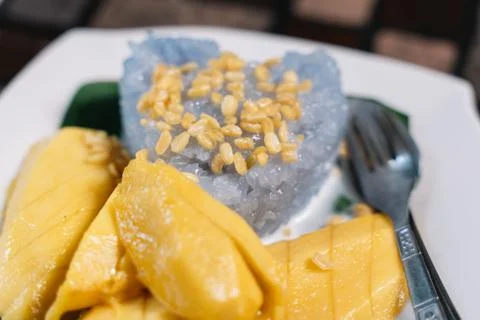 Mango Sticky Rice with a fork ans spoon on a wooden table Stock Photos