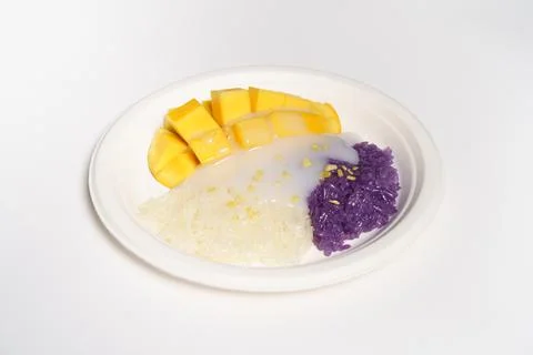 Mango sticky rice on a white paper plate on a white background, topped with c Stock Photos