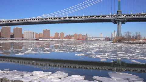 Manhattan Bridge reflects to the East River among Ice floes at Brooklyn. Video stock 337079878