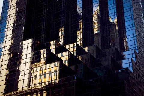 Manhattan building is reflected in the facade of a modern office building Stock Photos