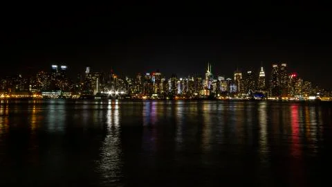 Manhattan skyline at night with reflections off water New York City NYC Stock Photos