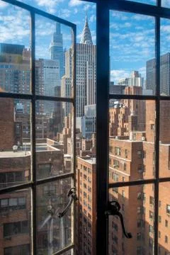 Manhattan skyline viewed through old fashioned open window. Stock Photos