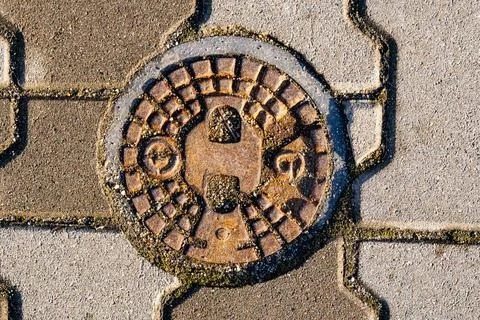 Manhole cover design embedded in pavement with texture and details in urban Stock Photos