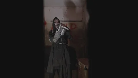 Maniac in the clothes of an executioner holds a chainsaw in his hands. Abandoned Stock Footage 238496089