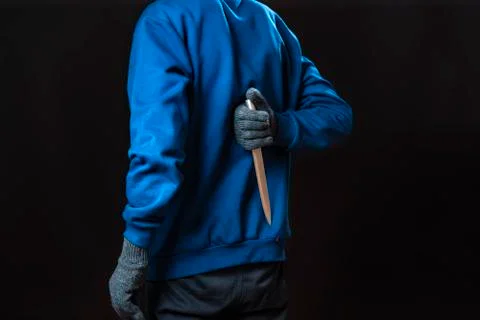 Maniac in gloves hold sharp knife behind his back and in pocket isolated Stock Photos