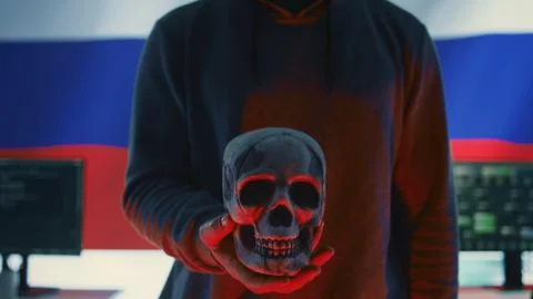 A maniacal russian hacker creating cyber threat alert by holding a skull Stock Photos