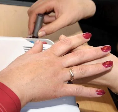 Manicure. Applying a thin brush pattern on the dark red base Stock Photos