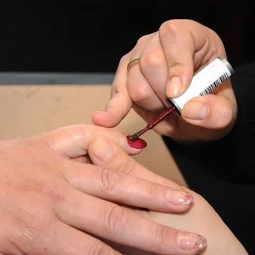Manicure. Applying a thin brush pattern on the dark red base Stock Photos
