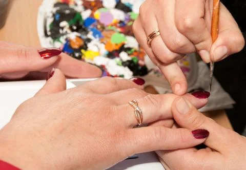 Manicure. Applying a thin brush pattern on the dark red base Stock Photos