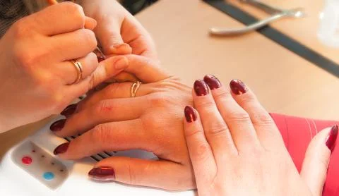 Manicure. Applying a thin brush pattern on the dark red base Stock Photos