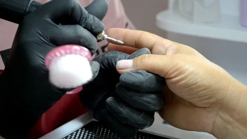 Manicure master in black gloves does hardware manicure, cleans finger of cuticle Stock Footage 122645390