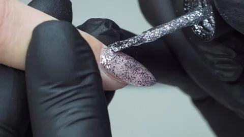 Manicure master covers nails client with silver varnish Stock Photos