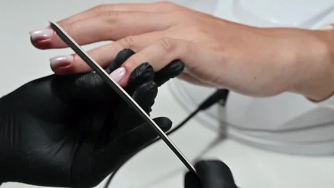 A manicure master does a manicure to a girl in the salon. Nails are filed with a Stock Footage 251854422