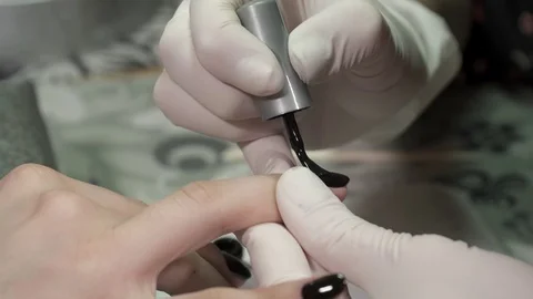 Manicure master in gloves covers nails with the black gel polish Stock Footage 73445429