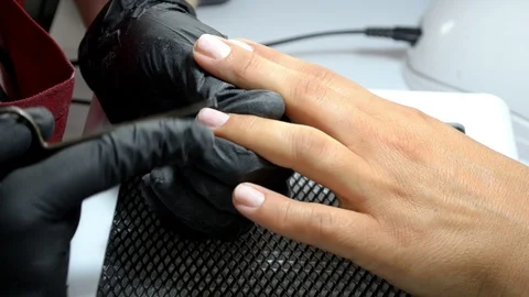 Manicure master in gloves cuts cuticle from client finger with thin scissors Stock Footage 122645482