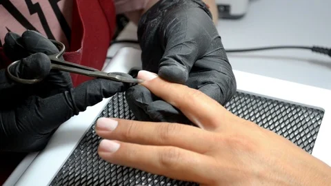 Manicure master in gloves cuts cuticle from client finger with thin scissors Stock Footage 122645514