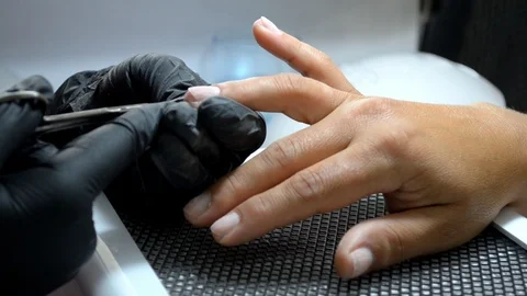 Manicure master in gloves cuts cuticle from client finger with thin scissors Stock Footage 122645541
