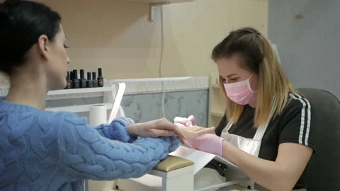The manicure master in the mask does the nail care on the hands of the manicure Video stock 105904548