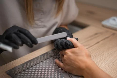 Manicure master sharpens nails close-up Stock Photos