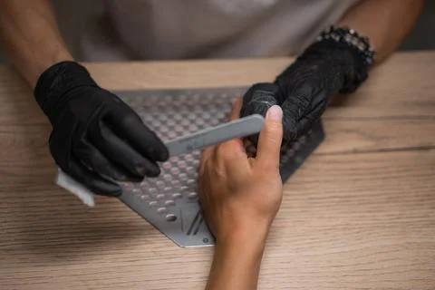 Manicure master sharpens nails close-up Stock Photos