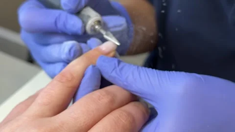 The manicure master uses an electric machine to file the clients nails in the Stock Footage 317697952