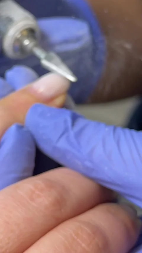 The manicure master uses an electric machine to file the clients nails in the Stock Footage 317916675