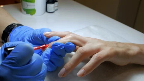 Manicure paints client's nails with red varnish in a beauty salon. Slow Motion Stock Footage 114314817